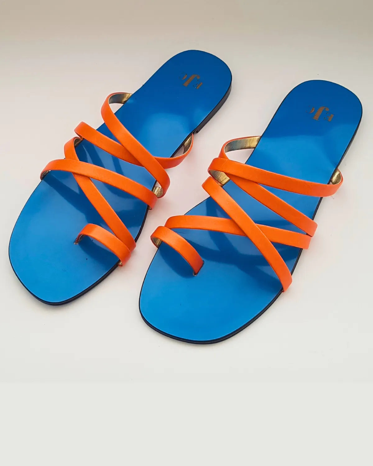 Blue sandals with orange straps on a light gray background