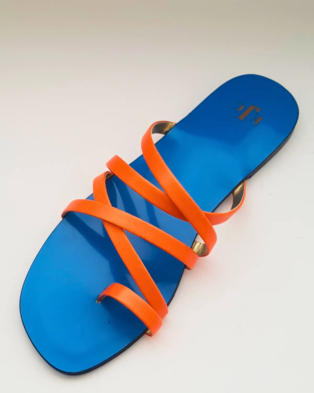 Blue sandal with orange straps on a light gray background