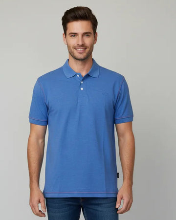 Man wearing a blue polo shirt and jeans on a light gray background