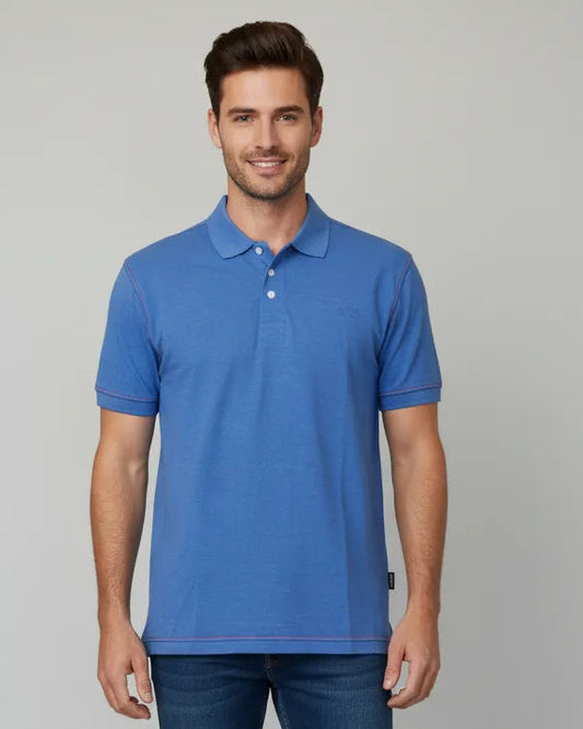 Man wearing a blue polo shirt and jeans on a light gray background