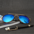 Blue sunglasses with gold frame on a magazine with a pen next to it