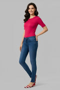 Woman wearing a pink top and blue jeans on a gray background