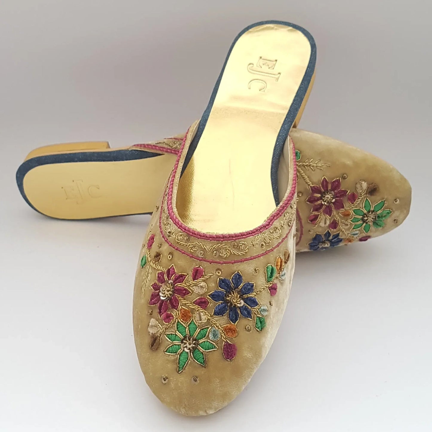 Decorative sandal with floral patterns and colorful stones on a white background
