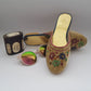 Decorative sandal with colorful embellishments, sunglasses, and a small box on a light gray background
