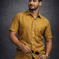Man wearing a mustard yellow shirt against a dark background