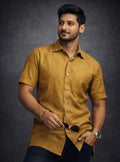 Man wearing a mustard yellow shirt against a dark background