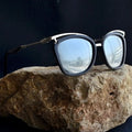 Sunglasses with reflective lenses on a rock, branded 'Element Jeans Co.'