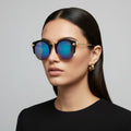 Woman wearing reflective sunglasses against a gray background