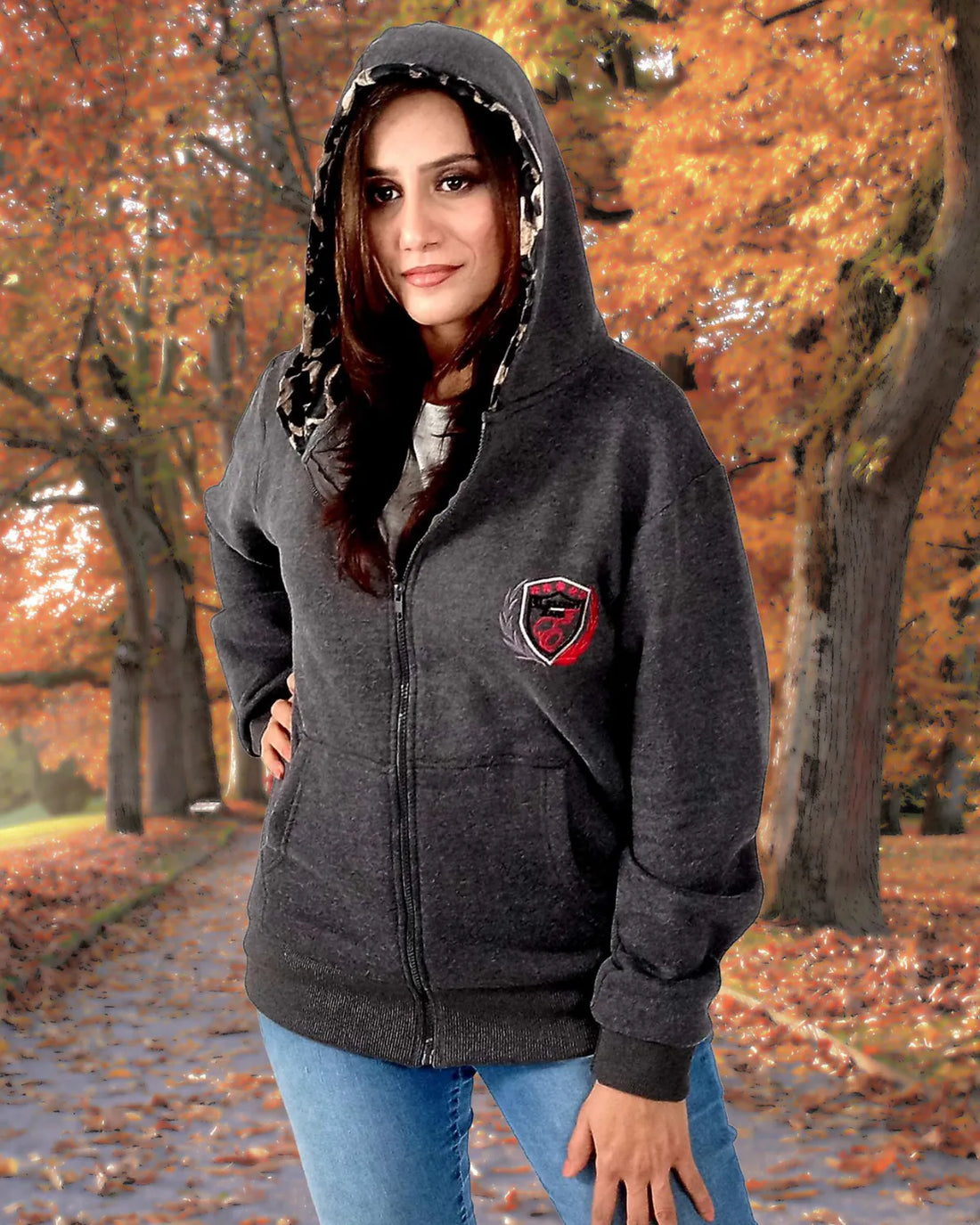 Woman wearing a dark gray hoodie with a logo in an autumn setting