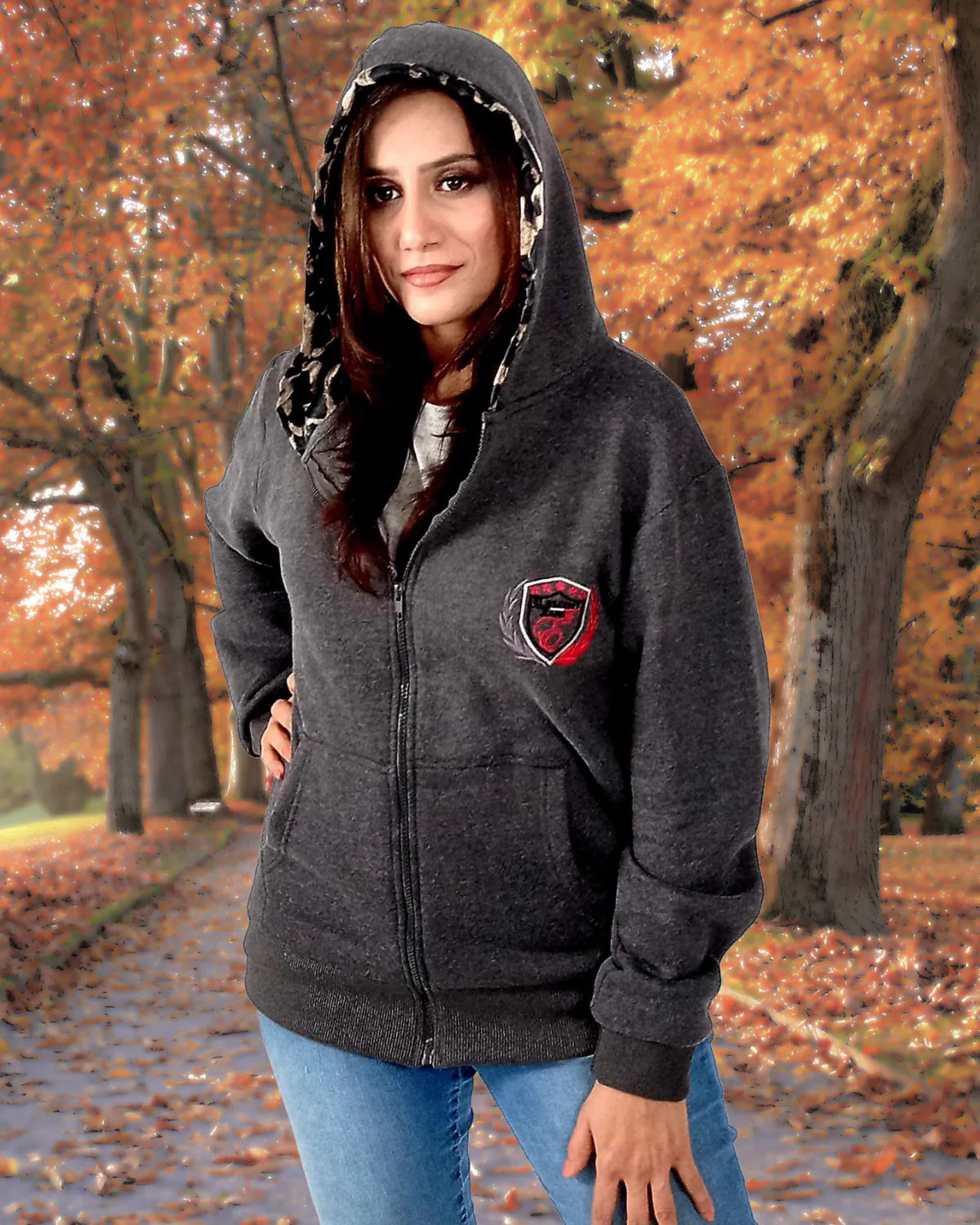 Woman wearing a dark gray hoodie with a logo in an autumn setting