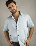 Man wearing a light blue shirt with a wooden background