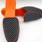 Pair of checkered loafers with orange accents on a white background