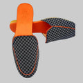 Pair of checkered loafers with orange accents on a white background