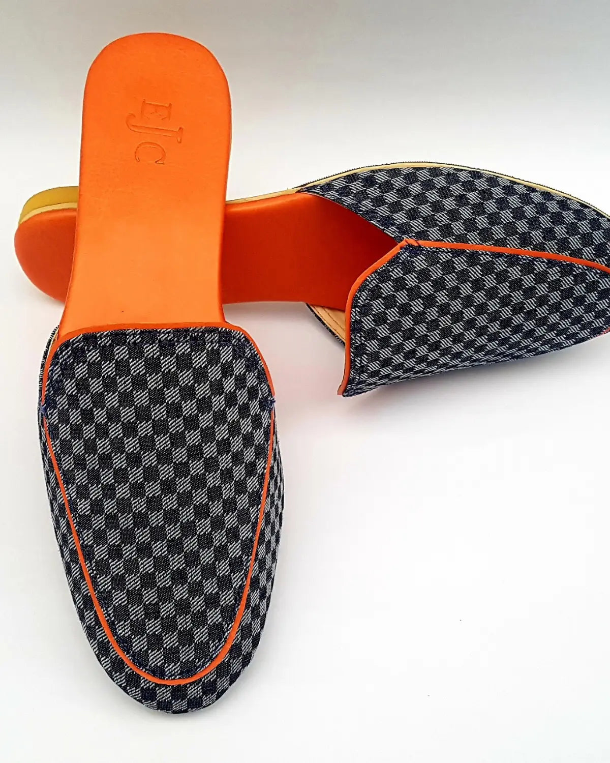 Pair of checkered loafers with orange accents on a white background