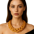 Woman wearing a large braided necklace against a neutral background
