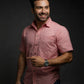 Man wearing a pink shirt and watch against a dark background