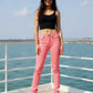 Woman wearing pink jeans and black top on a boat with water and sky in the background