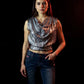 Woman wearing a silver sequin top and blue jeans against a dark background