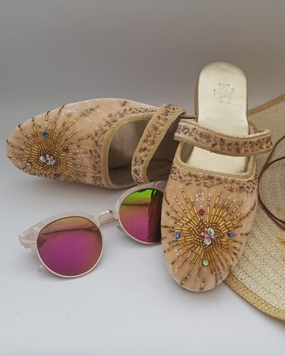 Cream color velvet mule shoes with beaded hand embroidery, displayed alongside sunglasses and a straw hat.