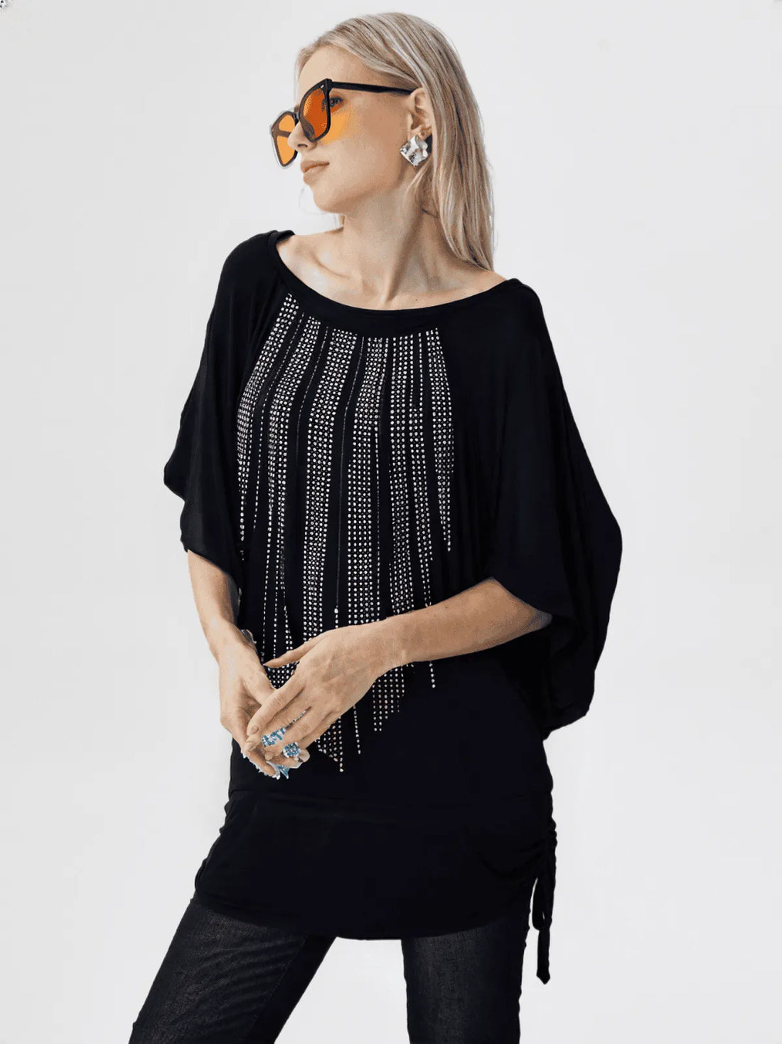 Woman wearing a black sweater with silver embellishments on a white background