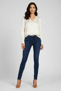 Woman wearing a white blouse and dark blue jeans on a gray background