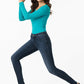 Woman wearing a turquoise top and dark blue jeans on a white background