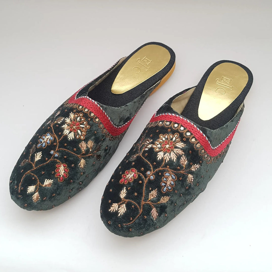 Pair of embroidered slippers with floral patterns on a white background
