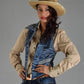 Woman wearing a beige shirt, denim overalls, and a straw hat on a gray background