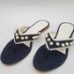 A pair of navy blue denim flip-flops embellished with white lace and pearls, displayed against a white background.