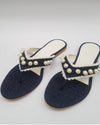 A pair of navy blue denim flip-flops embellished with white lace and pearls, displayed against a white background.
