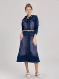 Woman wearing a long denim dress with a belt on a white background