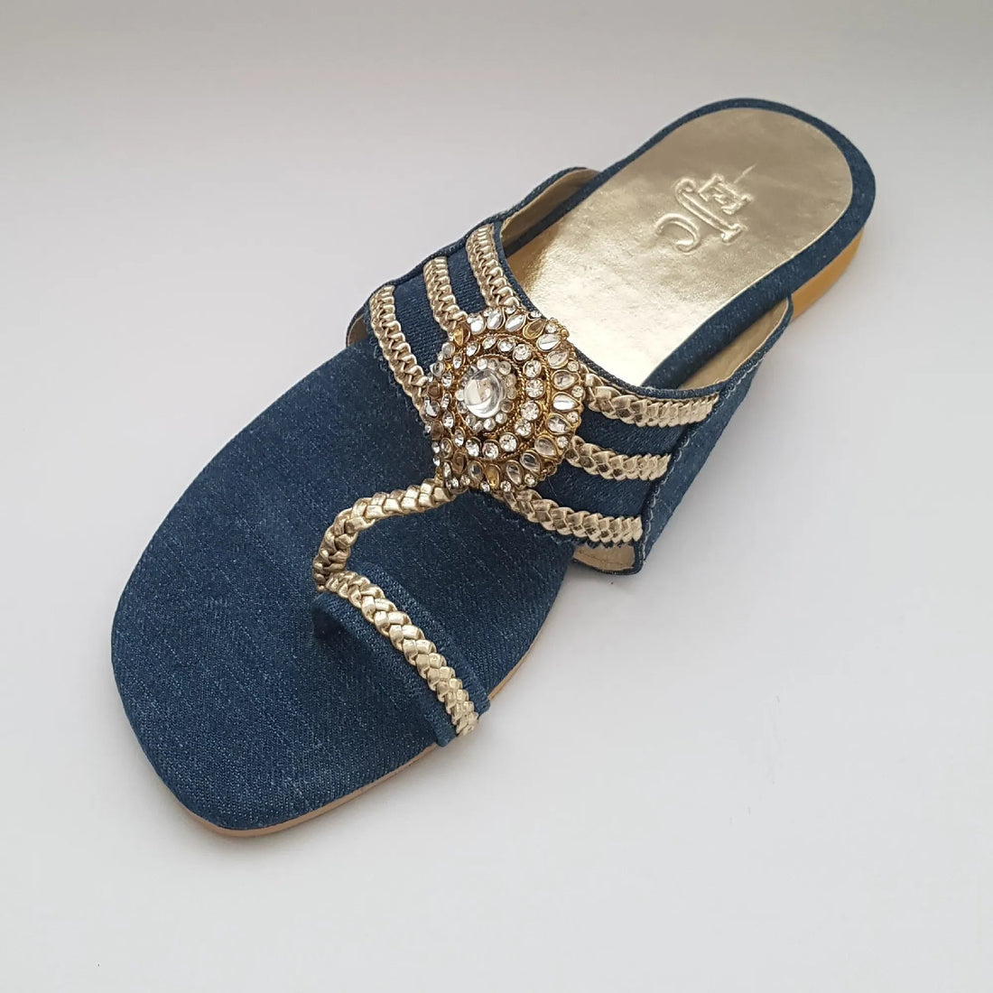 Pair of blue sandals with gold embellishments on a light gray background