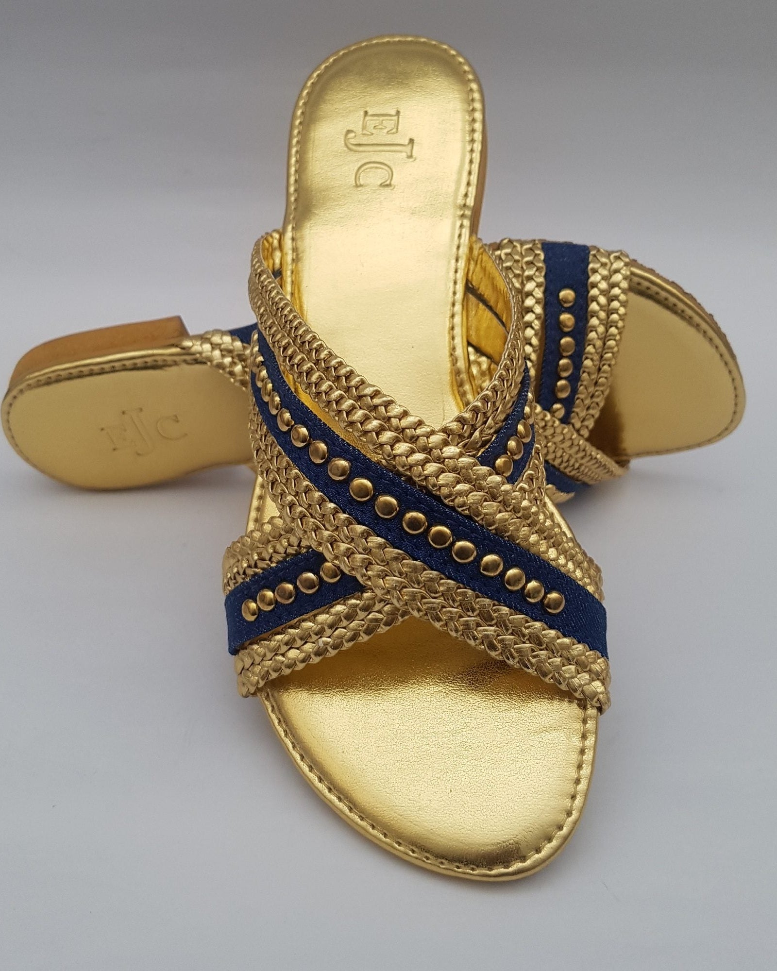 Gold sandal with blue strap on a gray background