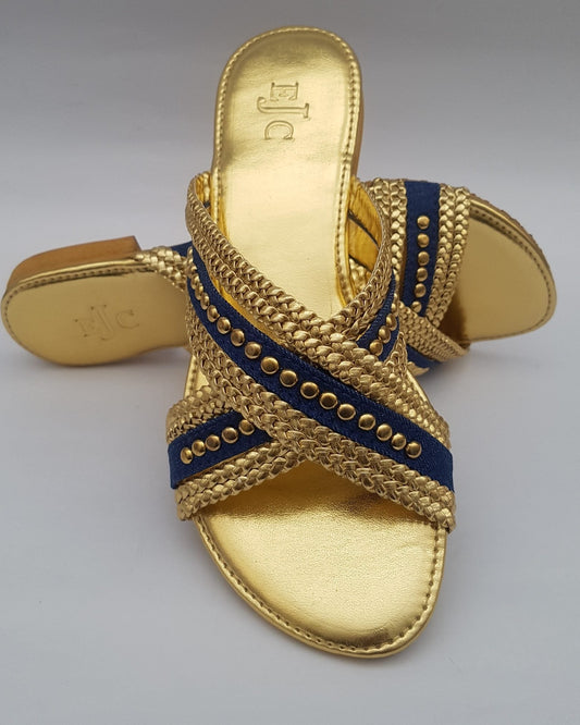 Gold sandal with blue strap on a gray background