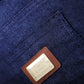 Close-up of a blue denim bag with a leather patch and brand logo.