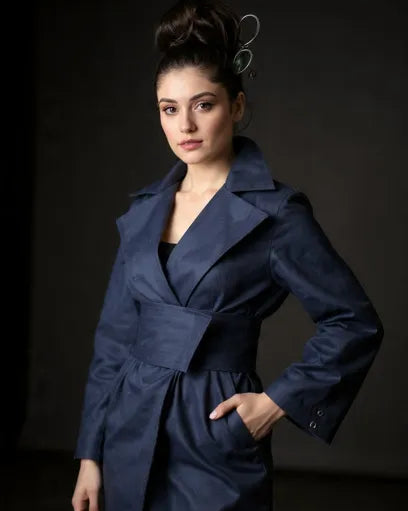 Woman wearing a navy blue trench coat against a dark background