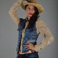Woman wearing a cowboy hat and denim vest against a gray background