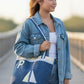 Denim tote bag with sailboat design and letter 'P' on a concrete surface
