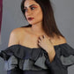 Woman wearing a black off-shoulder top against a gray background