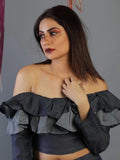 Woman wearing a black off-shoulder top against a gray background
