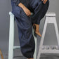 Person wearing blue denim pants sitting on a white stool against a gray background