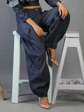Person wearing blue denim pants sitting on a white stool against a gray background