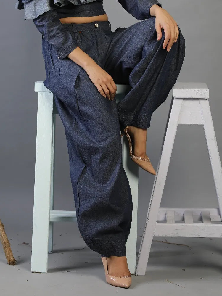 Person wearing blue denim pants sitting on a white stool against a gray background