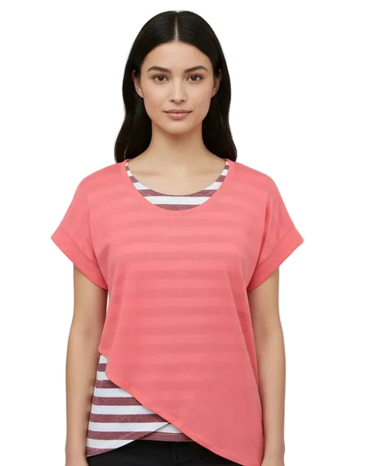Woman wearing a coral pink t-shirt over a striped shirt on a plain background