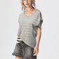 Woman wearing a gray sweater, denim skirt, and white cowboy boots on a white background
