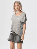 Woman wearing a gray sweater, denim skirt, and white cowboy boots on a white background