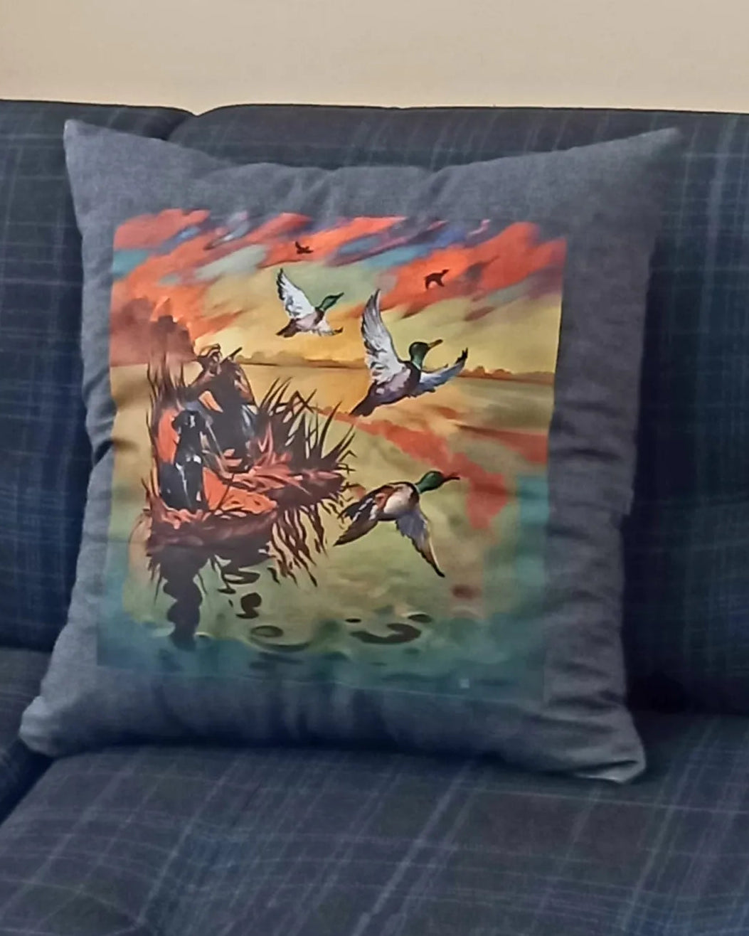 Decorative pillow with a hunting scene on a blue couch