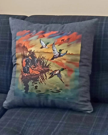 Decorative pillow with a hunting scene on a blue couch