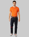 Man wearing an orange t-shirt and dark jeans on a white background