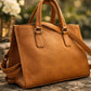 Dark Tan Faux leather handbag on a stone surface with a blurred floral background
